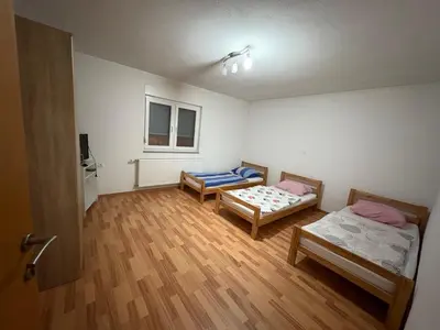 a room with two beds in a room with wooden floors at Sobe DANA in Teslić