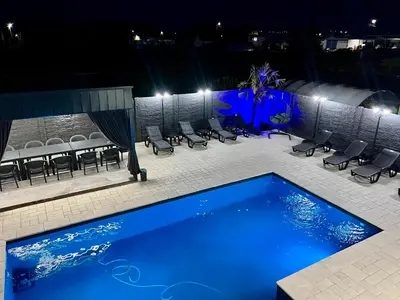 a swimming pool at night with chairs and a table at Villa Sunčani Raj in Gradačac