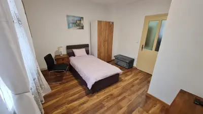 a bedroom with a bed and a desk and a chair at Sabina apartmani in Tuzla