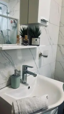 a bathroom sink with a faucet and a mirror at Sabina apartmani in Tuzla