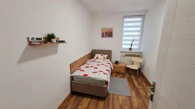 a small bedroom with a bed and a window at Sabina apartmani in Tuzla