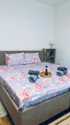 a bed with a bottle of wine on top of it at Sabina apartmani in Tuzla