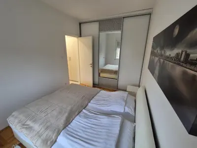 a small bedroom with a bed and a large mirror at Urban BL in Banja Luka