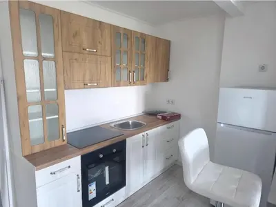 a kitchen with wooden cabinets and a sink and a white chair at Dora in Bugojno