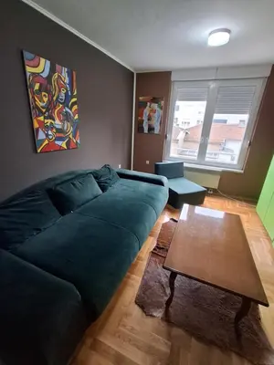 a living room with a green couch and a table at Studio apartman in Banja Luka