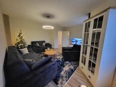 a living room with a christmas tree and black furniture at KRUNA Apartment in Cazin