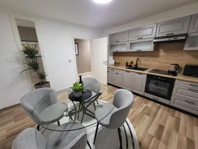 a kitchen with gray chairs and a table in a kitchen at KRUNA Apartment in Cazin