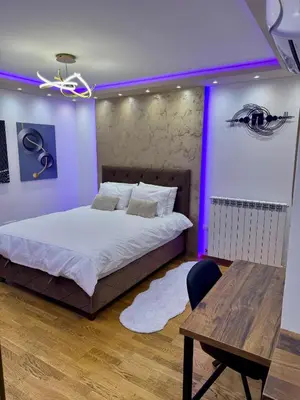 a bedroom with a bed and a table and purple lighting at Jelena Apartments in Banja Luka
