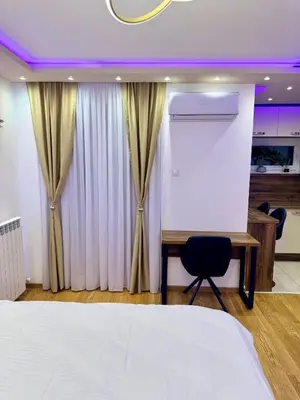 a bedroom with a bed and a desk and curtains at Jelena Apartments in Banja Luka