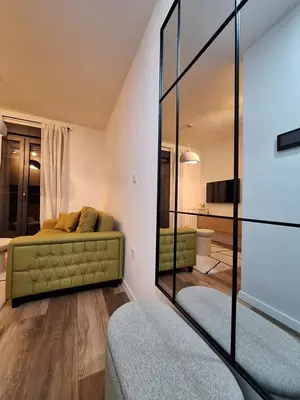 a living room with a green couch and a mirror at Urban Cube Apartment - Tuzla City Center in Tuzla