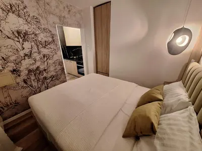 a bedroom with a white bed with a lamp on the wall at Urban Cube Apartment - Tuzla City Center in Tuzla