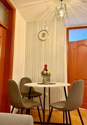 a table and chairs with a vase of flowers on it at Alexa Apartmani in Banja Luka