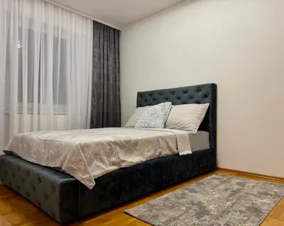 a bedroom with a black bed with a window at Alexa Apartmani in Banja Luka