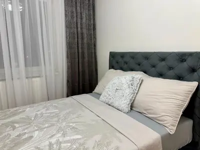 a bedroom with a bed with a blue headboard and a window at Alexa Apartmani in Banja Luka