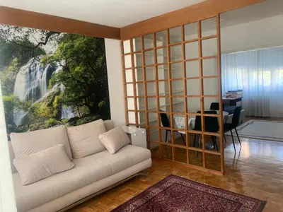 a living room with a white couch and a large painting at Slobo- stan na dan in Banja Luka