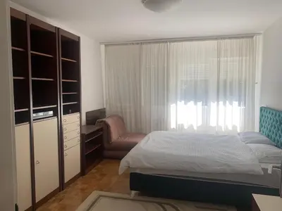 a bedroom with a bed and a chair and a window at Slobo- stan na dan in Banja Luka
