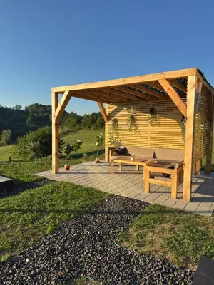 a wooden pergola with a bench on a patio at Harmony cottage in Banja Luka