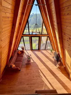 an attic room with a large window and a couch at Harmony cottage in Banja Luka