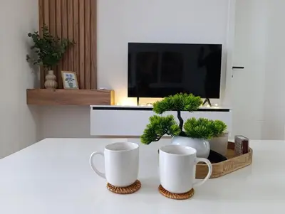 two white coffee mugs sitting on a table with plants at Apartman Home Away in Banja Luka