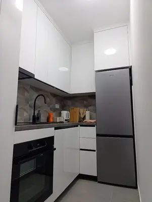 a kitchen with white cabinets and a black refrigerator at Apartman Home Away in Banja Luka
