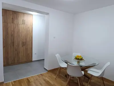 a dining room with a glass table and white chairs at Apartman Home Away in Banja Luka