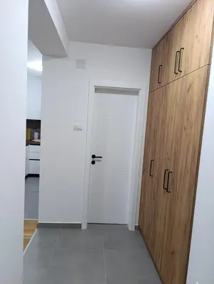 a hallway with a white door and wooden cabinets at Apartman Home Away in Banja Luka