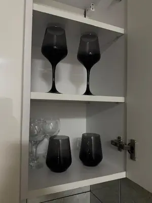 three wine glasses sitting on shelves in a cabinet at Apartman ARENA 2 Doboj in Doboj