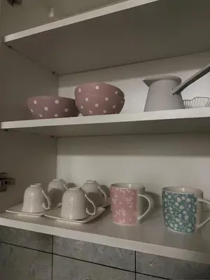 a shelf filled with cups and plates and bowls at Apartman ARENA 2 Doboj in Doboj