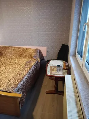 a bedroom with a bed and a table and a window at KONAK kod ODISEJE 3 in Tuzla