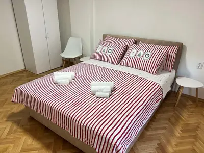 a bedroom with a large bed with red and white striped sheets at Apartman Zvjezdica in Banja Luka