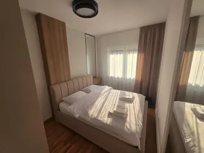 a bedroom with a white bed with a mirror at Apartman Damjan in Banja Luka