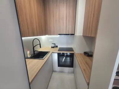 a small kitchen with wooden cabinets and a sink at Apartman Damjan in Banja Luka