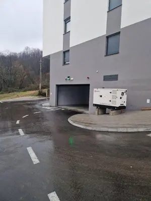 a building with a garage with a truck parked in a parking lot at Apartman Damjan in Banja Luka