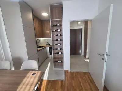 a room with a table and a kitchen with a door at Apartman Damjan in Banja Luka