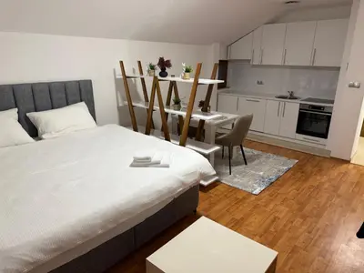a bedroom with a bed and a table and a kitchen at Papa Glisa in Banja Luka