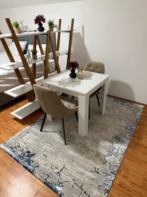 a white dining room table and chairs on a rug at Papa Glisa in Banja Luka