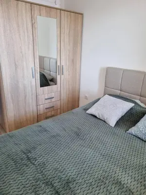 a bedroom with a bed and a cabinet with a mirror at Apartman Mila in Doboj