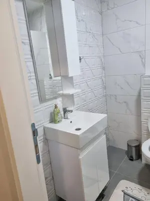 a white bathroom with a sink and a mirror at Apartman Mila in Doboj