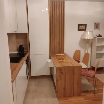 a small kitchen with a wooden table and a desk at Ella apartman in Banja Luka