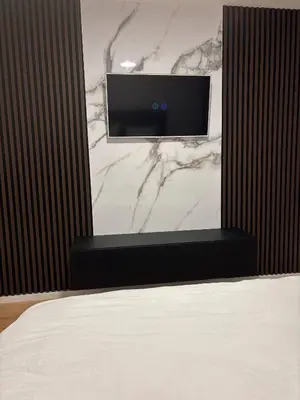 a bedroom with a bed and a tv on a marble wall at Apartman S52 in Doboj