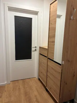 a door with a window next to a wooden cabinet at Apartman S52 in Doboj