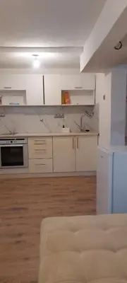 a kitchen with white cabinets and a wooden floor at Apartman Ani in Hiseti