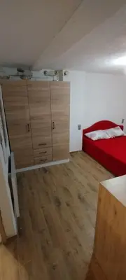 a bedroom with a red bed and wooden cabinets at Apartman Ani in Hiseti