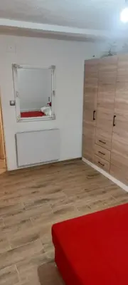 a bedroom with a red bed and a window at Apartman Ani in Hiseti