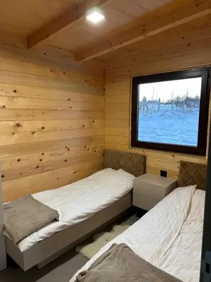 two beds in a log cabin with a window at Suncatcher Djurdjevic Apartmani in Banja Luka