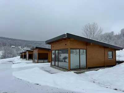 a log cabin with snow on the ground at Suncatcher Djurdjevic Apartmani in Banja Luka