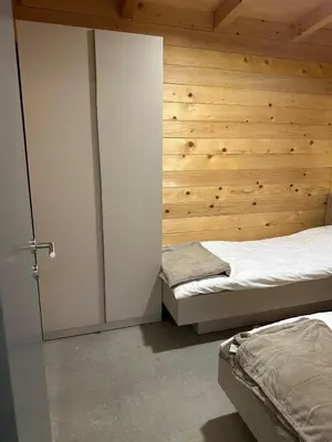 a bedroom with two beds and a wooden wall at Suncatcher Djurdjevic Apartmani in Banja Luka