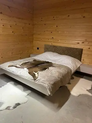 a bed in a room with a wooden wall at Suncatcher Djurdjevic Apartmani in Banja Luka