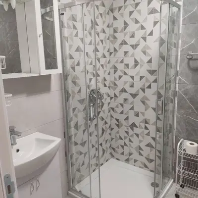 a shower with a glass door next to a sink at Apartman Ella in Železnička Stanica Incel