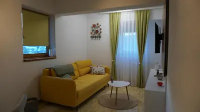 a living room with a yellow couch and a table at Apartmani Flocke Vlašić in Šišava